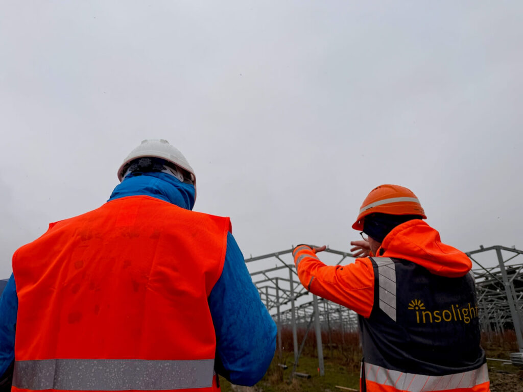 Insolight team members in safety gear observing metal structures on an agrivoltaic construction site.